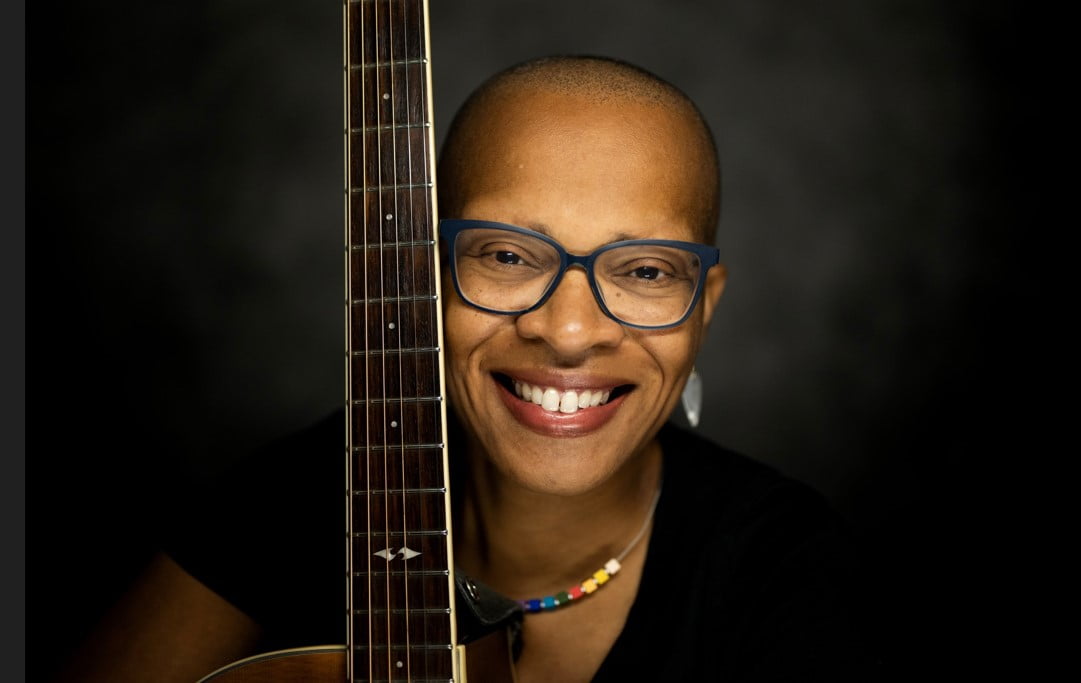 Musician Lea Morris smiling at the camera, holding her guitar